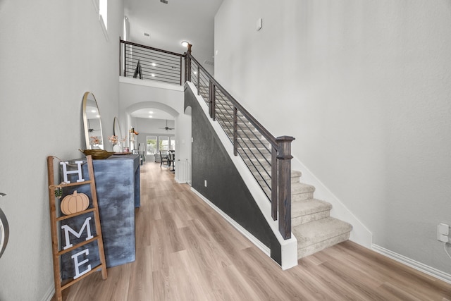 foyer with arched walkways, wood finished floors, a ceiling fan, and baseboards