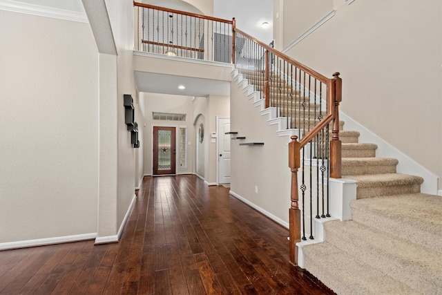 foyer featuring hardwood / wood-style flooring, stairs, a high ceiling, and baseboards