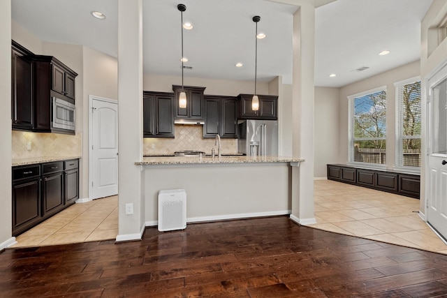 kitchen with visible vents, appliances with stainless steel finishes, light stone counters, light wood-type flooring, and pendant lighting