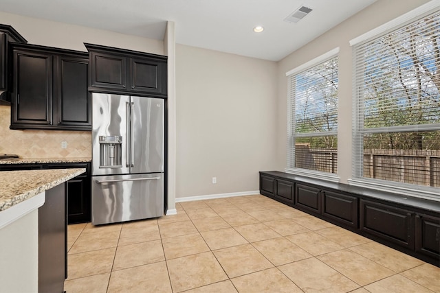 kitchen with light tile patterned floors, high quality fridge, visible vents, and backsplash