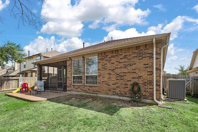 rear view of house featuring a yard, central AC, and brick siding