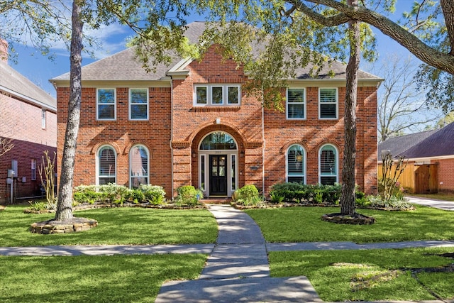 view of front of home featuring a front lawn, fence, and brick siding