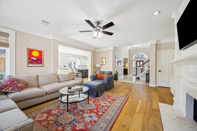 living area featuring stairway, plenty of natural light, visible vents, and a premium fireplace