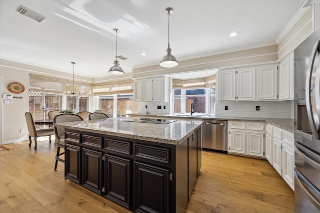 kitchen with visible vents, a sink, stainless steel appliances, white cabinets, and light wood-type flooring