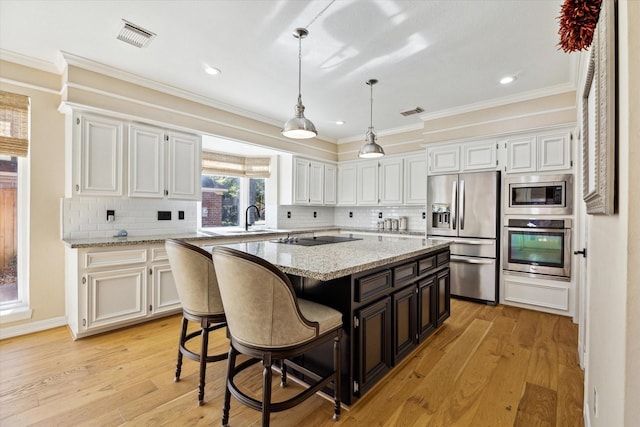 kitchen featuring light wood-type flooring, appliances with stainless steel finishes, ornamental molding, and a center island