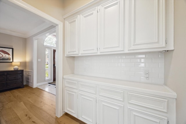 kitchen featuring light wood finished floors, white cabinets, light countertops, and ornamental molding