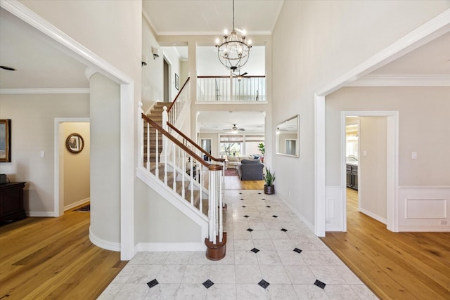 entryway with stairway, wood finished floors, a towering ceiling, and ornamental molding