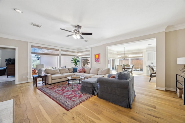 living area featuring light wood finished floors, visible vents, baseboards, and ornamental molding