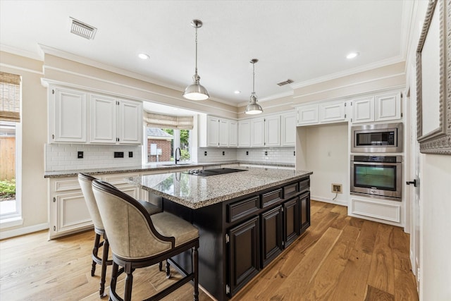 kitchen featuring light wood-style floors, appliances with stainless steel finishes, a kitchen island, and white cabinetry