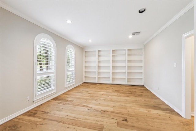 empty room featuring visible vents, baseboards, crown molding, and light wood-type flooring