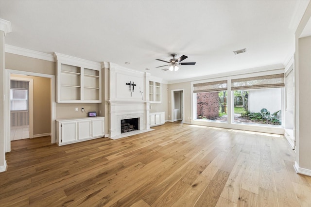unfurnished living room with a ceiling fan, visible vents, a high end fireplace, light wood-type flooring, and baseboards