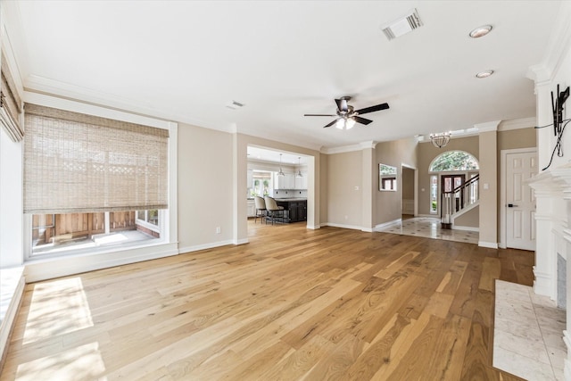unfurnished living room with light wood finished floors, visible vents, a healthy amount of sunlight, and ceiling fan with notable chandelier