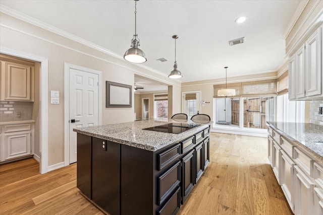 kitchen with visible vents, light wood-type flooring, black electric cooktop, and tasteful backsplash