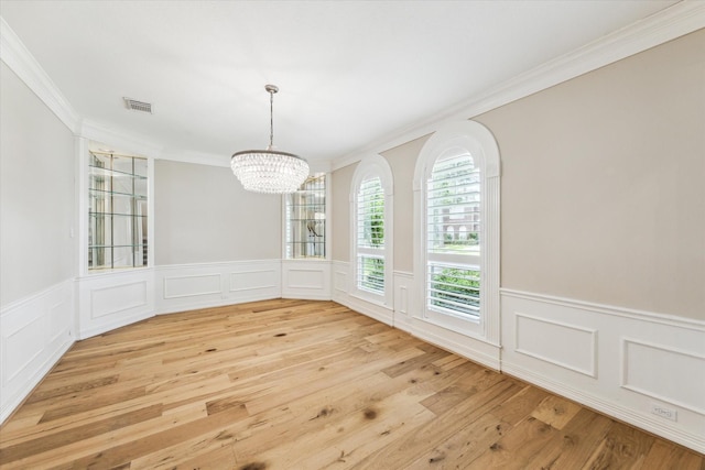 unfurnished dining area with visible vents, ornamental molding, an inviting chandelier, a decorative wall, and light wood-style floors