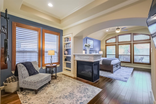 bedroom with a fireplace, arched walkways, dark wood-type flooring, and ornamental molding