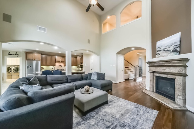 living area with arched walkways, dark wood finished floors, a fireplace, visible vents, and separate washer and dryer