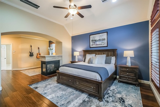 bedroom featuring arched walkways, ornamental molding, visible vents, and hardwood / wood-style flooring