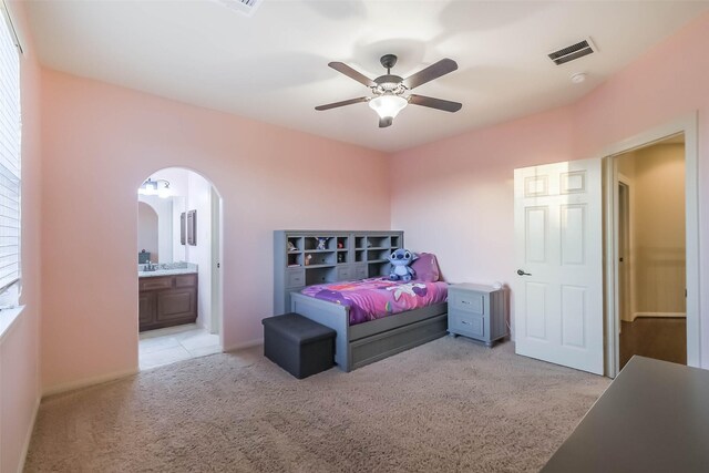 bedroom featuring visible vents, arched walkways, connected bathroom, and light colored carpet