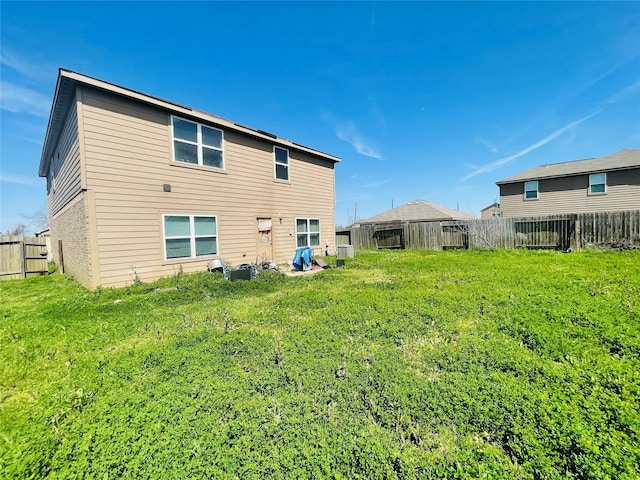 back of property featuring a fenced backyard and a lawn