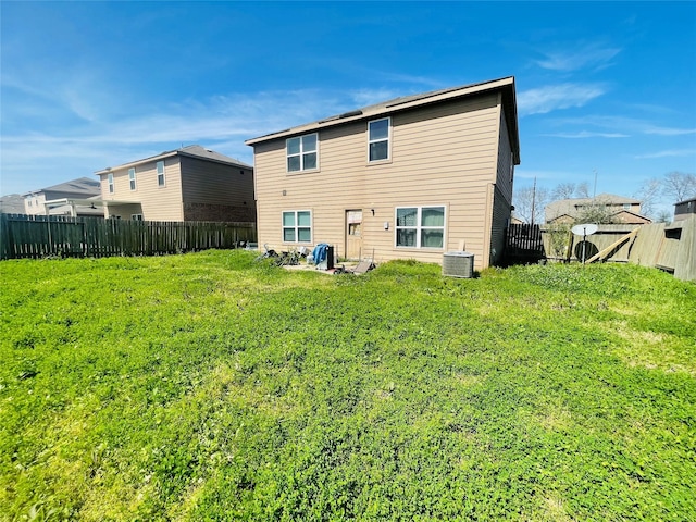 rear view of house with a fenced backyard, a gate, and a yard