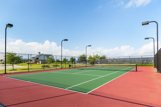 view of tennis court featuring community basketball court and fence