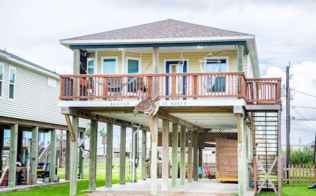 back of property featuring a carport, covered porch, roof with shingles, and stairway