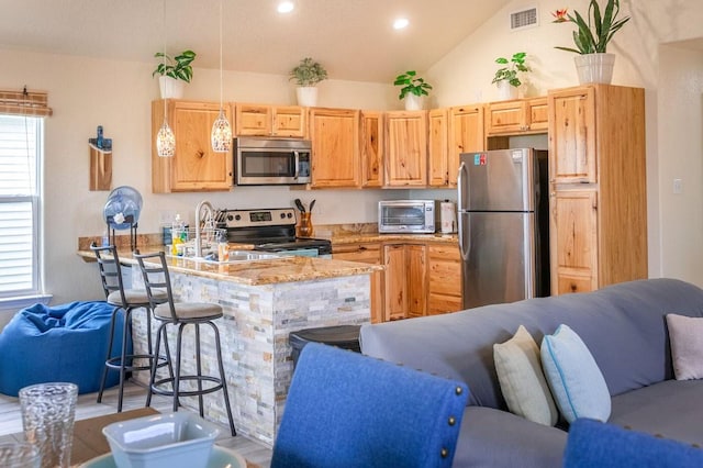 kitchen with stainless steel appliances, open floor plan, visible vents, and a kitchen breakfast bar