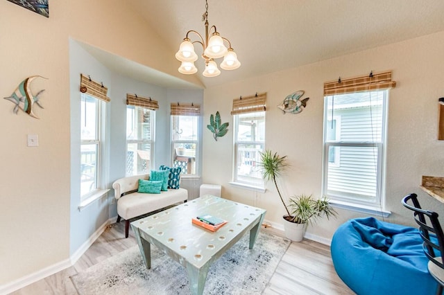 sitting room with light wood-type flooring, baseboards, vaulted ceiling, and a notable chandelier