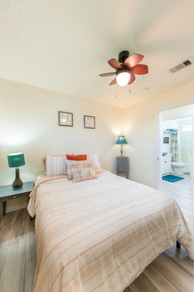 bedroom with a ceiling fan, visible vents, connected bathroom, and wood finished floors