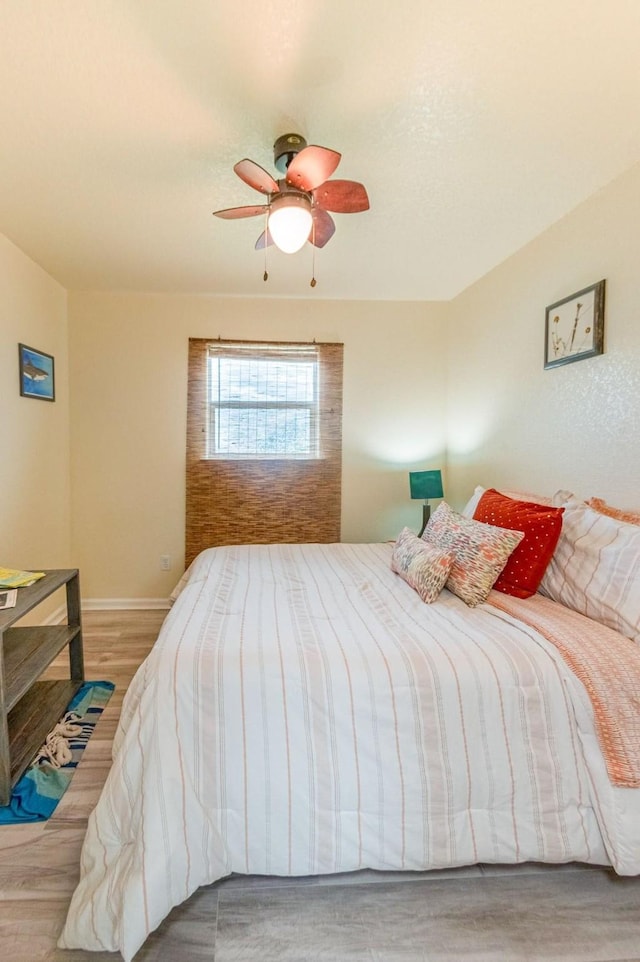 bedroom with ceiling fan, baseboards, and wood finished floors