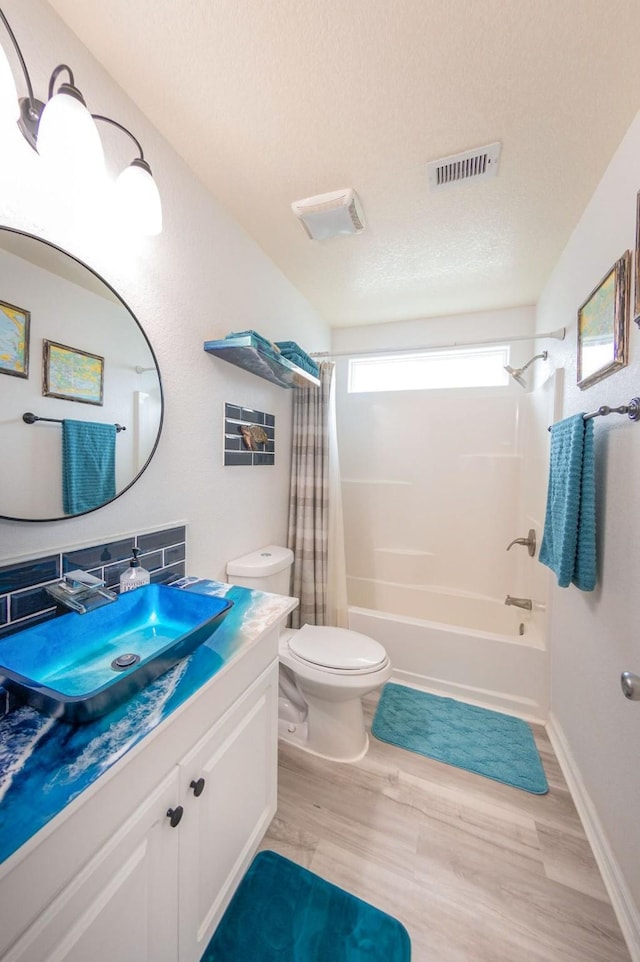 full bath with visible vents, toilet, wood finished floors, shower / bath combo with shower curtain, and vanity