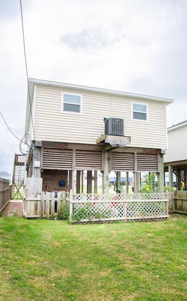 rear view of house featuring central AC, fence, and a lawn