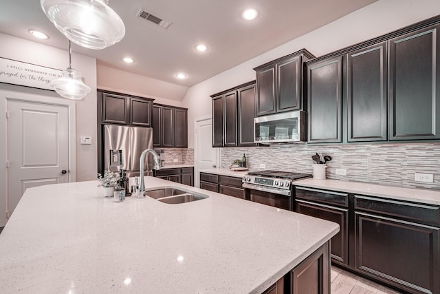 kitchen with stainless steel appliances, a sink, visible vents, decorative backsplash, and light stone countertops