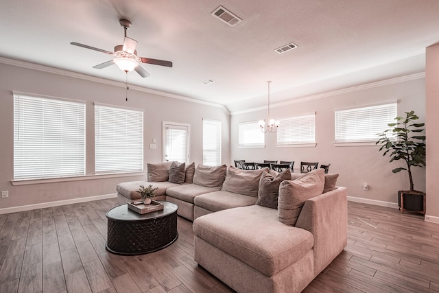 living area featuring ornamental molding, wood finished floors, visible vents, and a healthy amount of sunlight