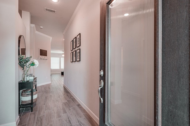 corridor featuring light wood-type flooring, visible vents, crown molding, and baseboards