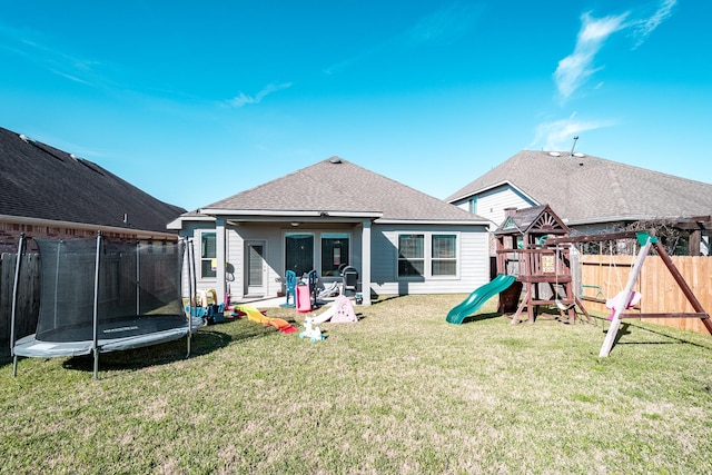 rear view of property with a playground, a fenced backyard, a yard, a trampoline, and a patio area