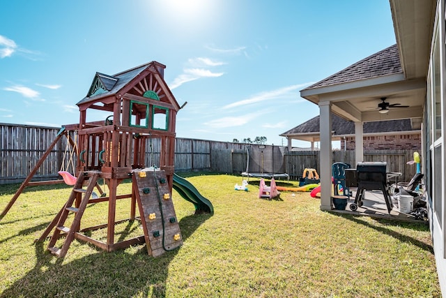 view of jungle gym featuring a fenced backyard, a trampoline, ceiling fan, and a lawn