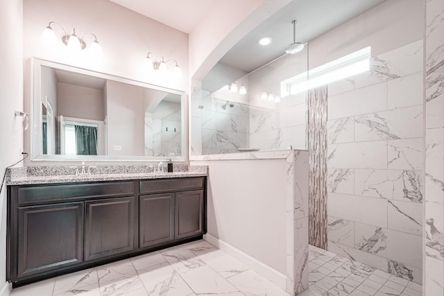 bathroom featuring marble finish floor, double vanity, a sink, and walk in shower