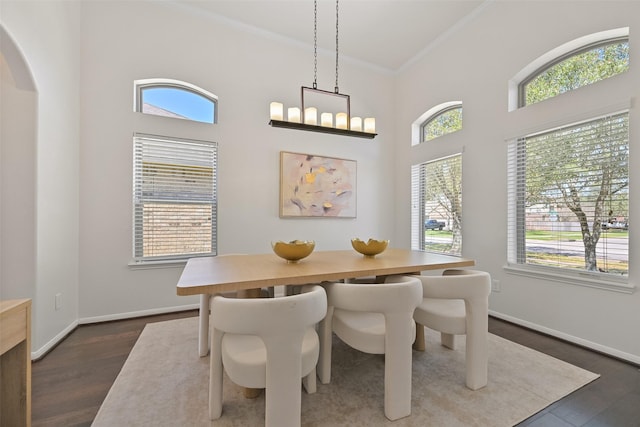 dining space featuring crown molding, baseboards, dark wood-style flooring, and arched walkways