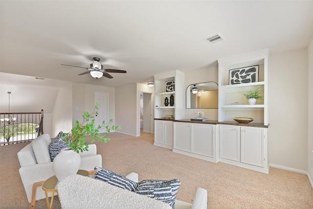 living room featuring visible vents, baseboards, light colored carpet, and ceiling fan with notable chandelier