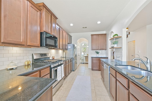 kitchen with visible vents, open shelves, dark stone countertops, stainless steel appliances, and a sink