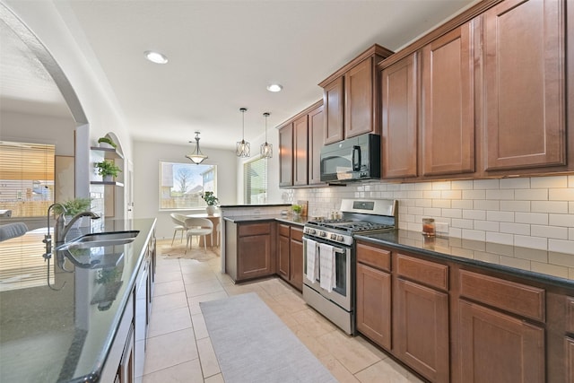 kitchen with tasteful backsplash, black microwave, gas range, a peninsula, and arched walkways