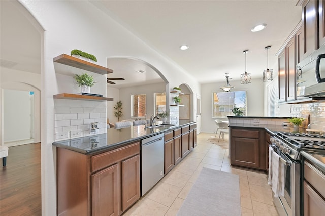 kitchen with a sink, stainless steel appliances, open shelves, and tasteful backsplash