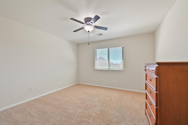 empty room with visible vents, light colored carpet, a ceiling fan, and baseboards