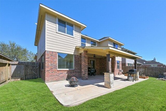 back of house featuring a patio, a yard, a fenced backyard, a fire pit, and brick siding