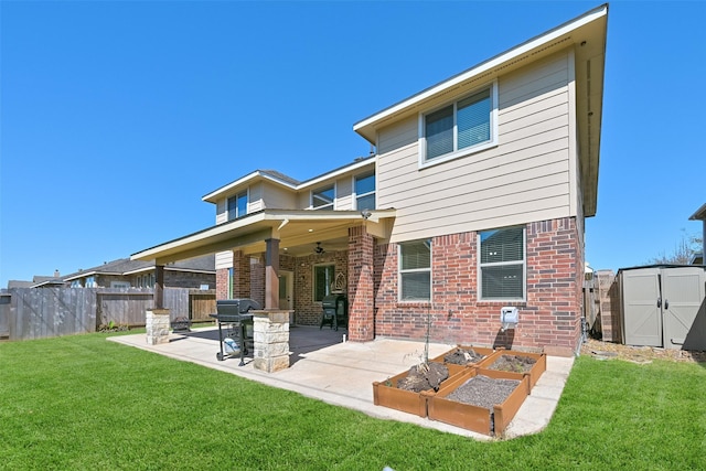 back of property with a storage unit, fence, a yard, an outdoor structure, and brick siding