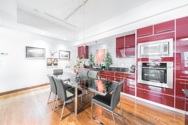 dining space with light wood-type flooring, rail lighting, and baseboards