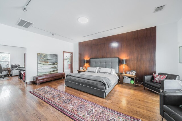 bedroom with visible vents, track lighting, and wood finished floors