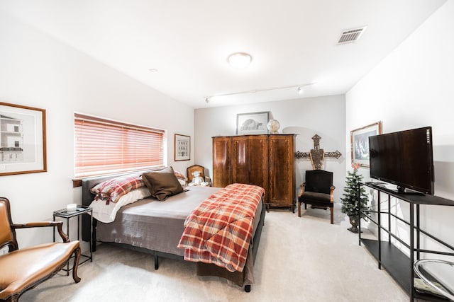 bedroom with light carpet, visible vents, and track lighting