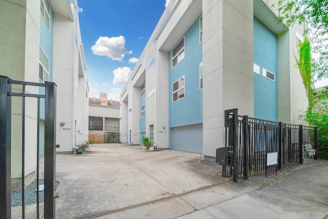 view of property exterior with an attached garage, fence, and concrete driveway